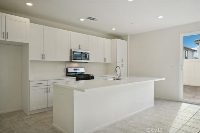 kitchen featuring sink, white cabinets, appliances with stainless steel finishes, and a center island with sink