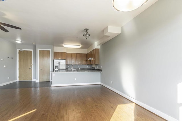 kitchen featuring ceiling fan, kitchen peninsula, sink, dark wood-type flooring, and stainless steel fridge