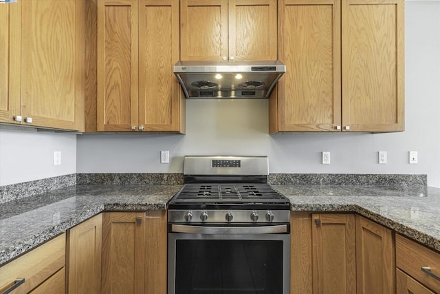 kitchen featuring stainless steel gas range oven, dark stone countertops, and range hood