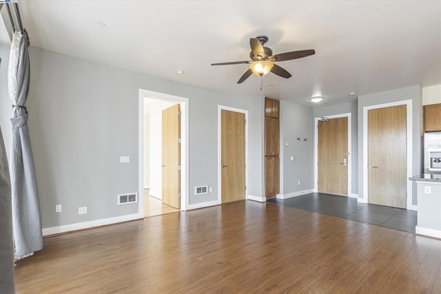 unfurnished living room with ceiling fan and dark wood-type flooring