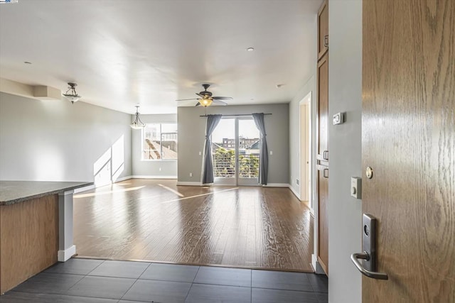 unfurnished living room featuring ceiling fan and dark tile patterned floors