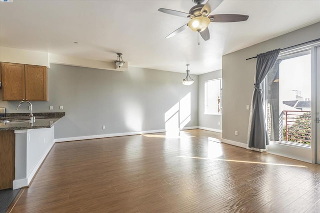 unfurnished living room featuring ceiling fan, dark hardwood / wood-style floors, and sink