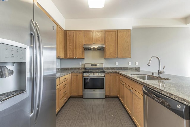 kitchen with stainless steel appliances, kitchen peninsula, dark stone counters, and sink