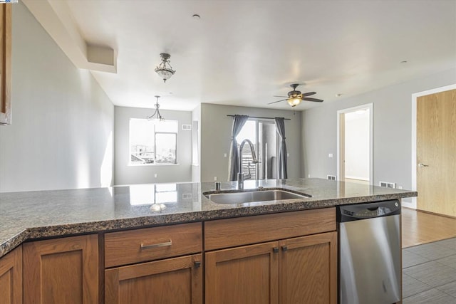 kitchen featuring stainless steel dishwasher, dark stone counters, sink, ceiling fan, and light tile patterned floors