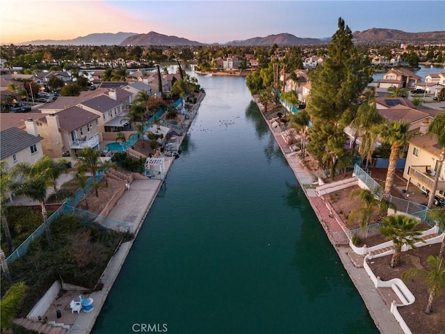 aerial view at dusk featuring a water and mountain view