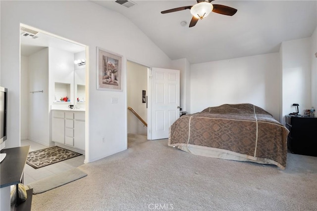 bedroom with vaulted ceiling, ceiling fan, light colored carpet, and ensuite bath