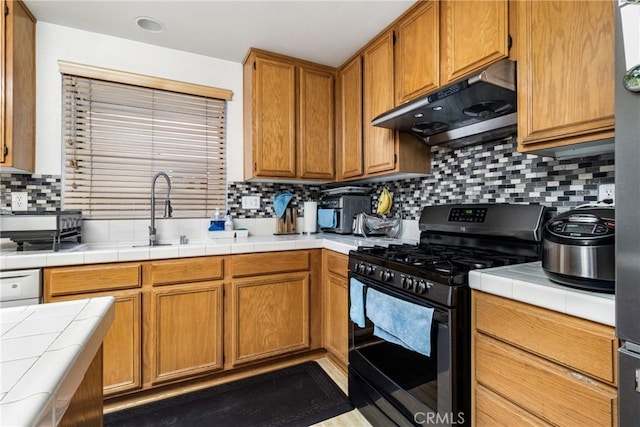 kitchen featuring decorative backsplash, sink, black gas stove, tile counters, and dishwashing machine