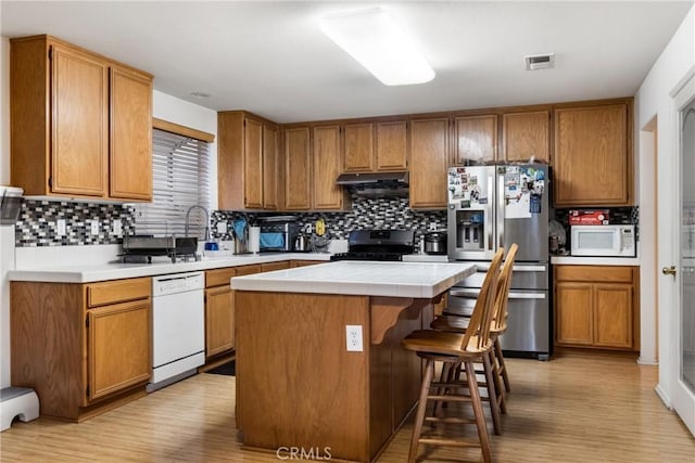 kitchen with white appliances, a center island, tile counters, tasteful backsplash, and a kitchen breakfast bar