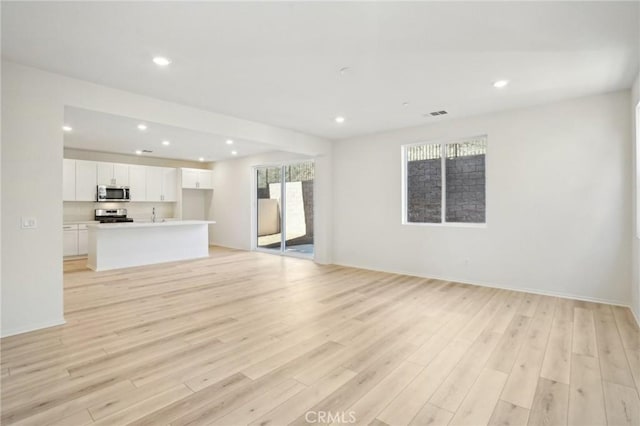 34260 Summer Ln, Yucaipa, CA 92399 - unfurnished living room featuring light wood-type flooring, recessed lighting, a sink, and baseboards