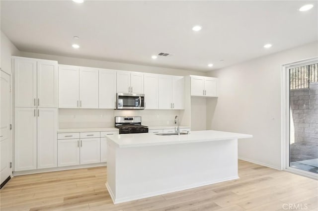 34260 Summer Ln, Yucaipa, CA 92399 - kitchen featuring stainless steel appliances, a sink, white cabinetry, light countertops, and an island with sink