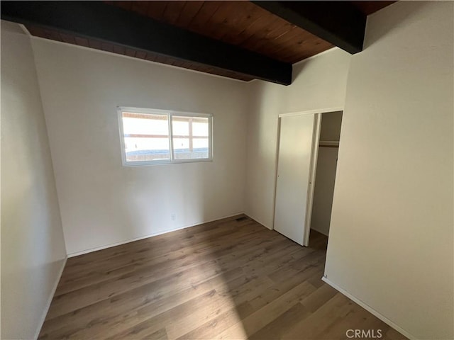 unfurnished bedroom featuring a closet, wood ceiling, beamed ceiling, and light hardwood / wood-style flooring