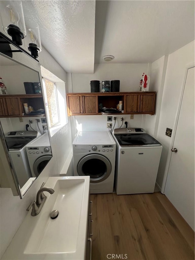 washroom featuring cabinets, hardwood / wood-style floors, a textured ceiling, and independent washer and dryer