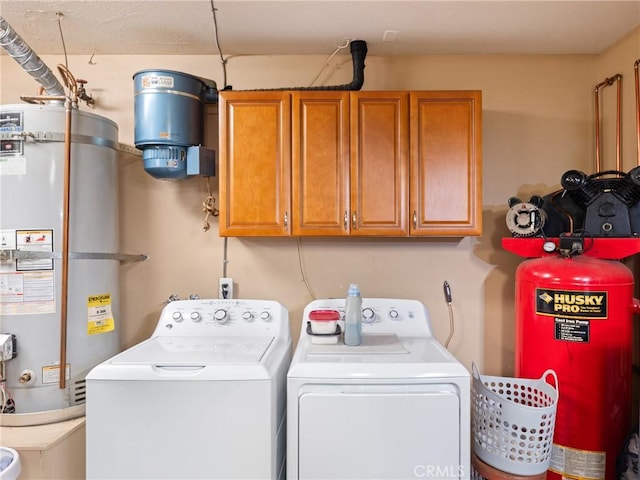 clothes washing area with cabinets, secured water heater, and washing machine and clothes dryer