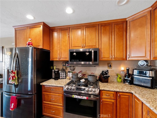 kitchen featuring appliances with stainless steel finishes and light stone counters