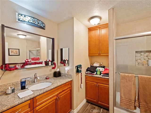 bathroom featuring a textured ceiling, a shower with door, hardwood / wood-style floors, and vanity