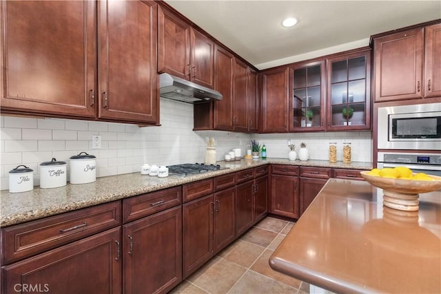 kitchen featuring backsplash, appliances with stainless steel finishes, and light stone counters