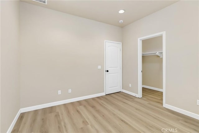 unfurnished bedroom featuring light wood-type flooring, a closet, and a walk in closet