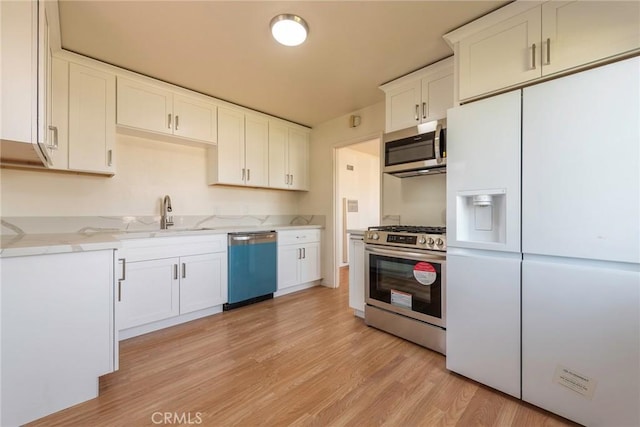 kitchen with white cabinetry, light hardwood / wood-style floors, appliances with stainless steel finishes, light stone countertops, and sink