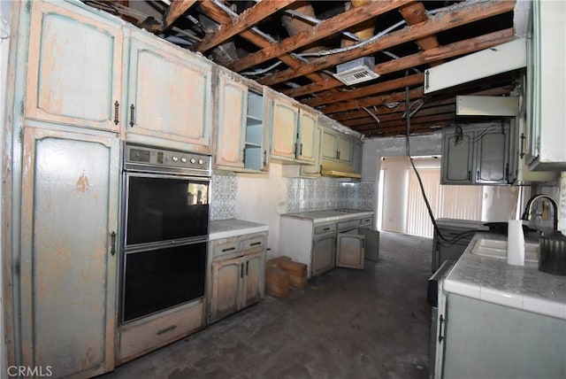 kitchen with backsplash, black double oven, and sink