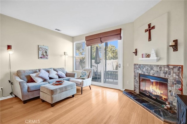 living room with a tiled fireplace and hardwood / wood-style floors