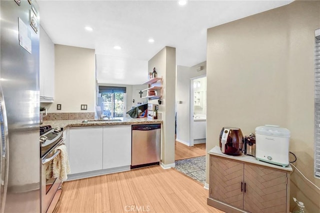 kitchen with light hardwood / wood-style floors, sink, stainless steel appliances, and white cabinetry