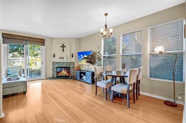 dining space featuring a tiled fireplace, a notable chandelier, and hardwood / wood-style floors