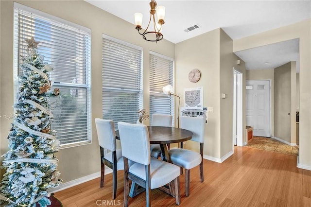 dining area with an inviting chandelier and light hardwood / wood-style flooring