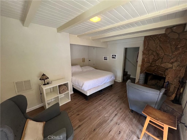 bedroom with a fireplace, beamed ceiling, and hardwood / wood-style flooring