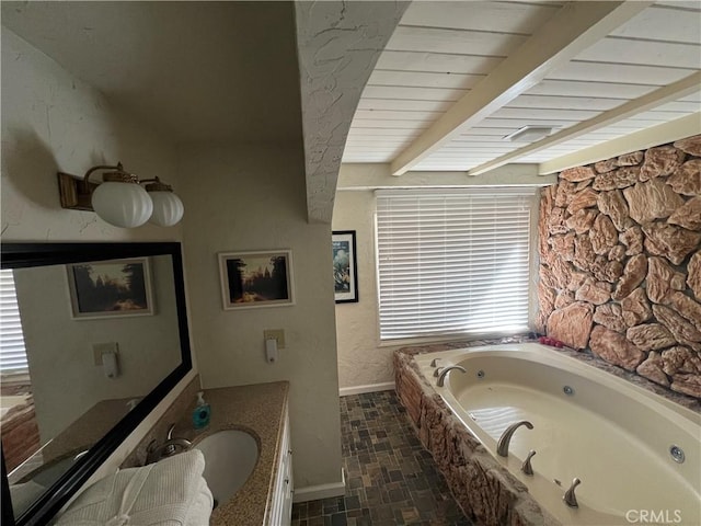 bathroom with a tub to relax in, vanity, and beam ceiling