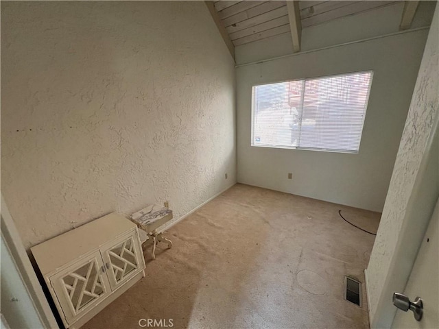 carpeted spare room featuring vaulted ceiling with beams and wooden ceiling