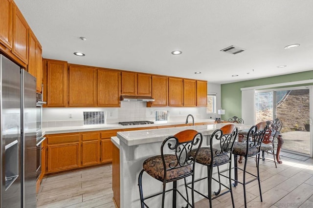 kitchen featuring appliances with stainless steel finishes, a kitchen breakfast bar, a center island, and light hardwood / wood-style flooring