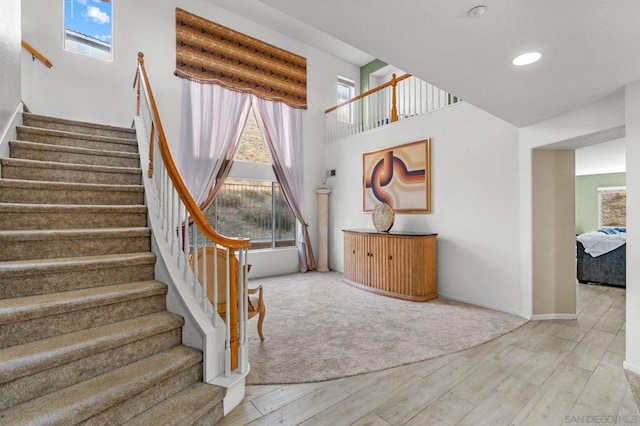 stairs with hardwood / wood-style flooring and a high ceiling