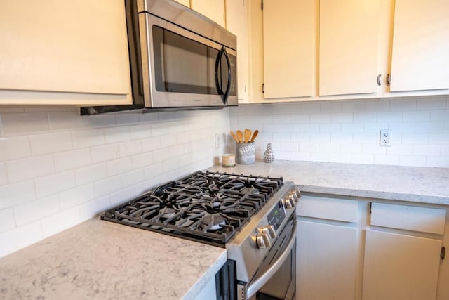 kitchen with light stone counters, tasteful backsplash, and appliances with stainless steel finishes