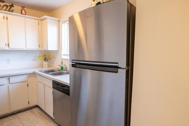 kitchen featuring sink, white cabinets, decorative backsplash, light tile patterned floors, and stainless steel appliances