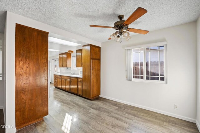 kitchen with ceiling fan, a textured ceiling, and light hardwood / wood-style flooring