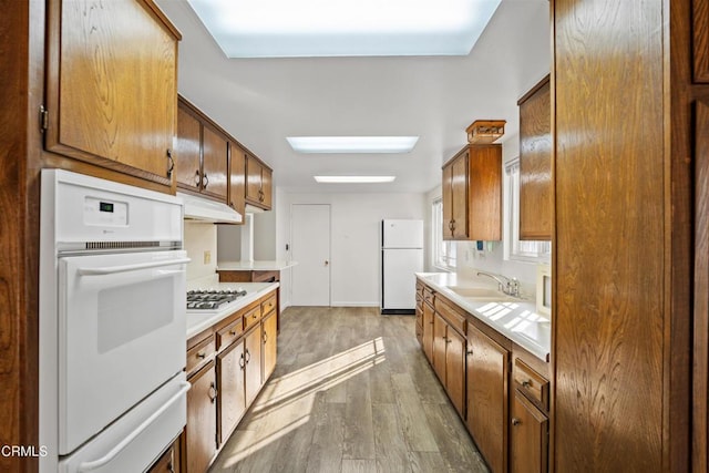 kitchen featuring sink, white appliances, and hardwood / wood-style flooring