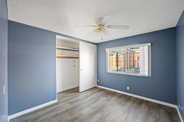 unfurnished bedroom featuring ceiling fan, wood-type flooring, a closet, and a textured ceiling