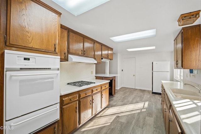 kitchen with sink, white appliances, and light hardwood / wood-style flooring