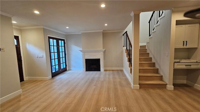 unfurnished living room featuring crown molding, light hardwood / wood-style flooring, and french doors