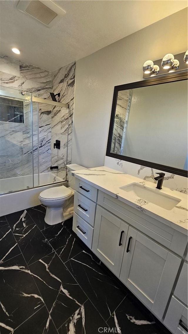 full bathroom featuring vanity, bath / shower combo with glass door, and toilet