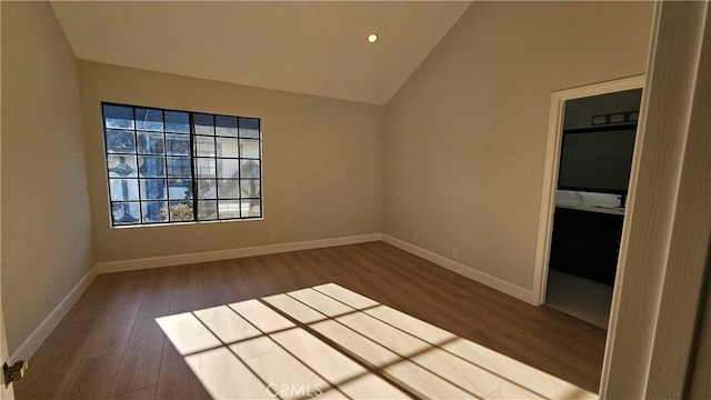 empty room with vaulted ceiling and hardwood / wood-style floors