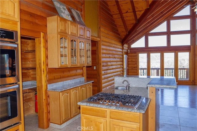 kitchen with light stone countertops, sink, log walls, and stainless steel appliances