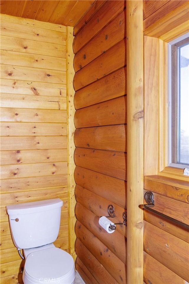 bathroom with toilet, wood ceiling, and rustic walls