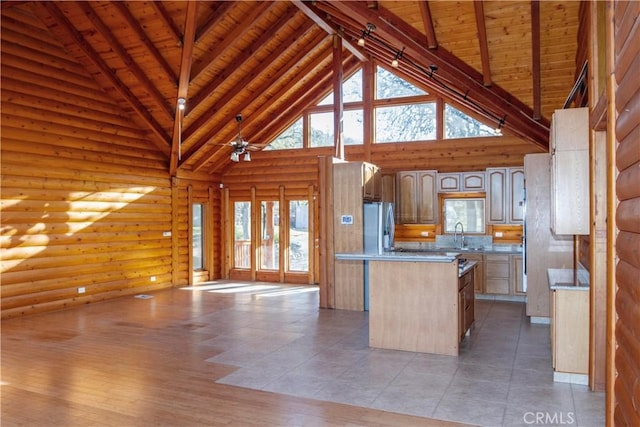 kitchen with a center island, high vaulted ceiling, stainless steel refrigerator, rustic walls, and beamed ceiling