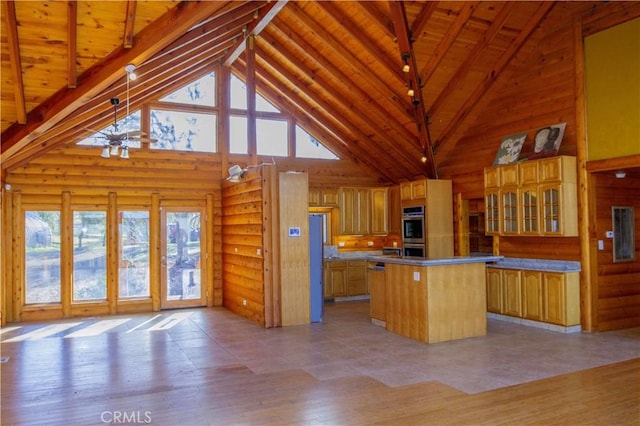 kitchen with high vaulted ceiling, log walls, pendant lighting, and a center island