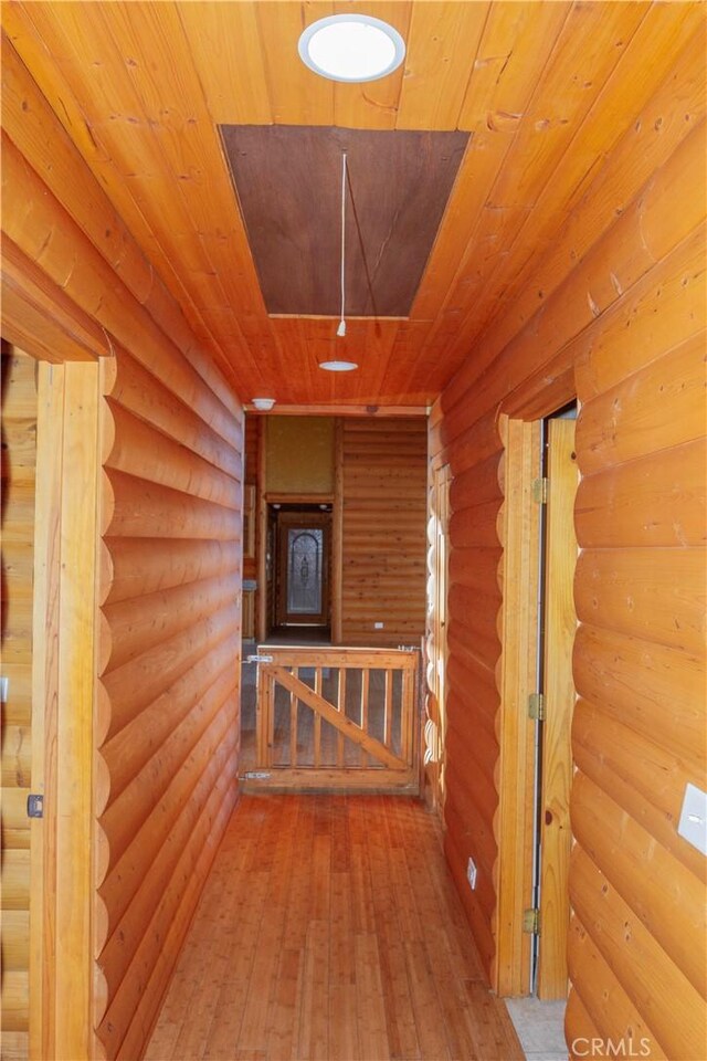 corridor featuring hardwood / wood-style floors, rustic walls, and wooden ceiling