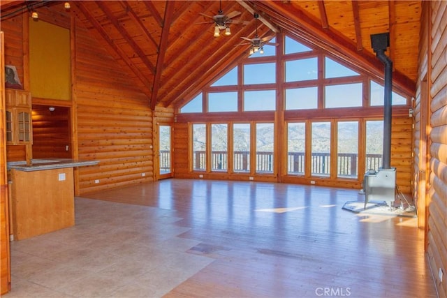 unfurnished living room with high vaulted ceiling, plenty of natural light, and log walls