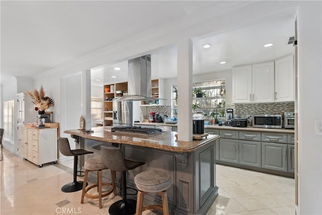 kitchen featuring island range hood, stainless steel appliances, dark stone countertops, a center island, and gray cabinets