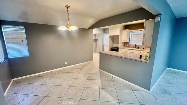 kitchen with pendant lighting, white cabinetry, sink, a notable chandelier, and light tile patterned floors