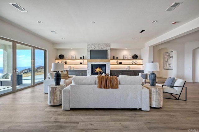 living room featuring light wood-type flooring and a stone fireplace